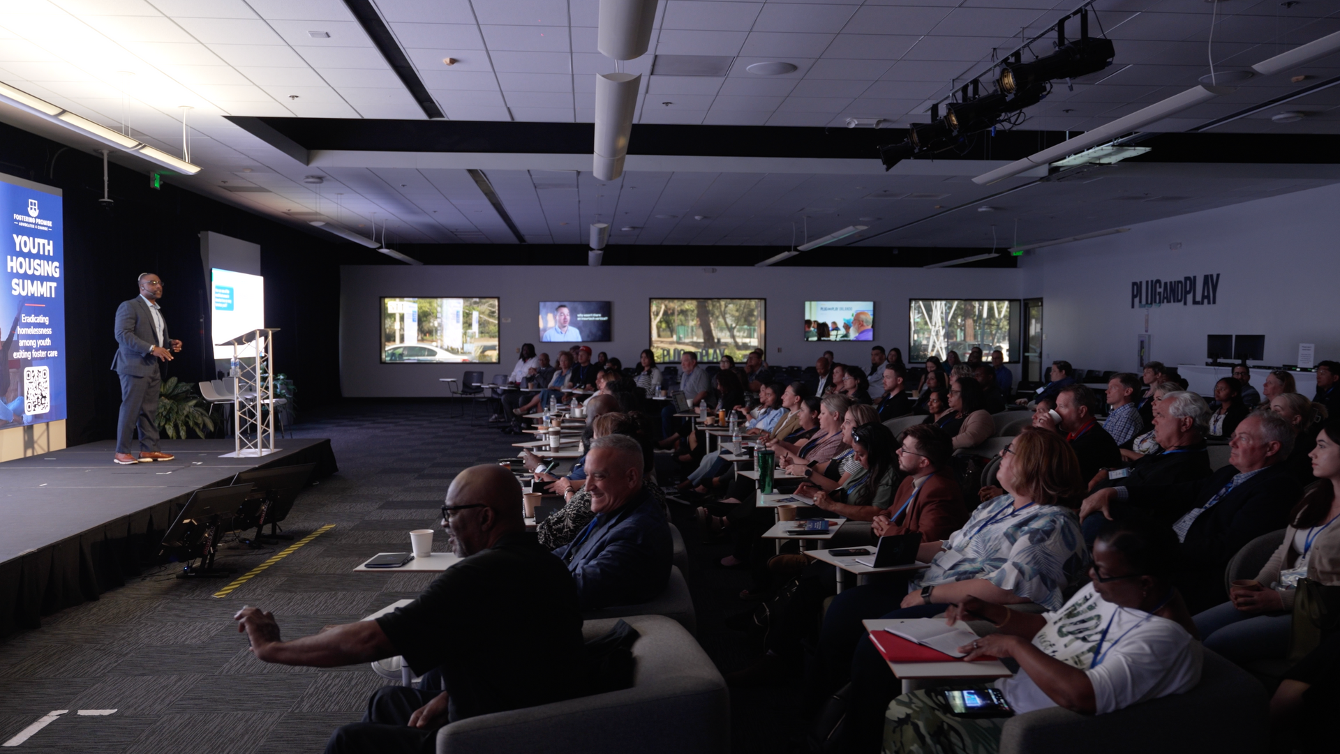 Conference audience watching a presentation on a stage in a dark auditorium