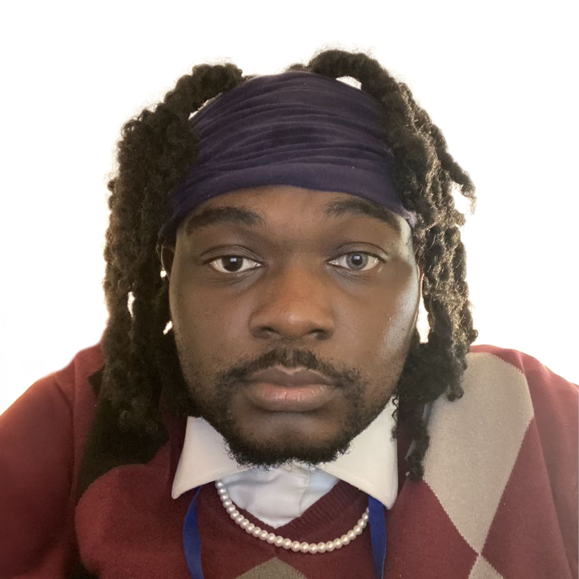 Close-up portrait of a person with dark locs, a purple headband, and a red argyle sweater, looking at the camera