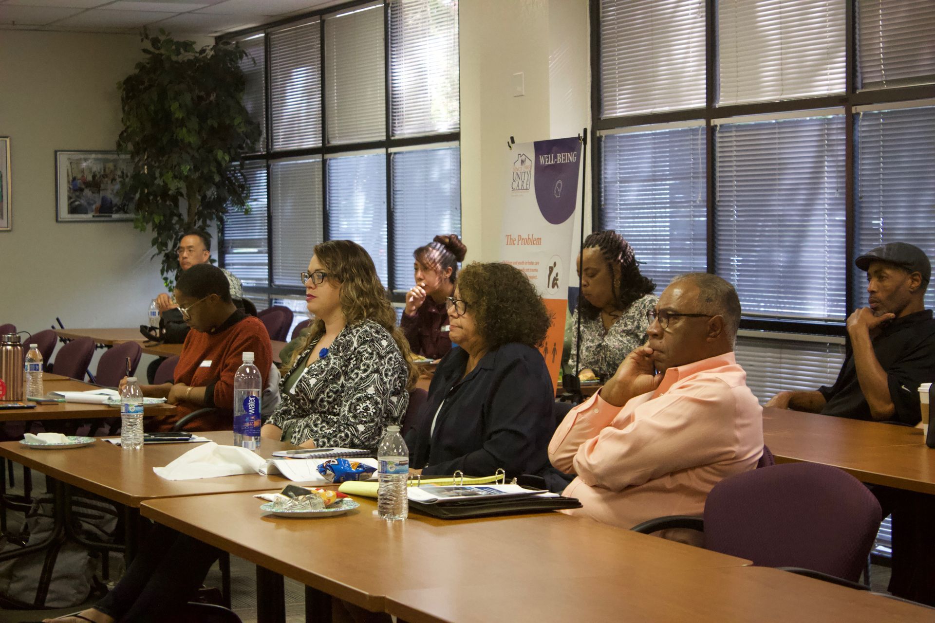 People seated at a conference table in a meeting room, listening attentively.