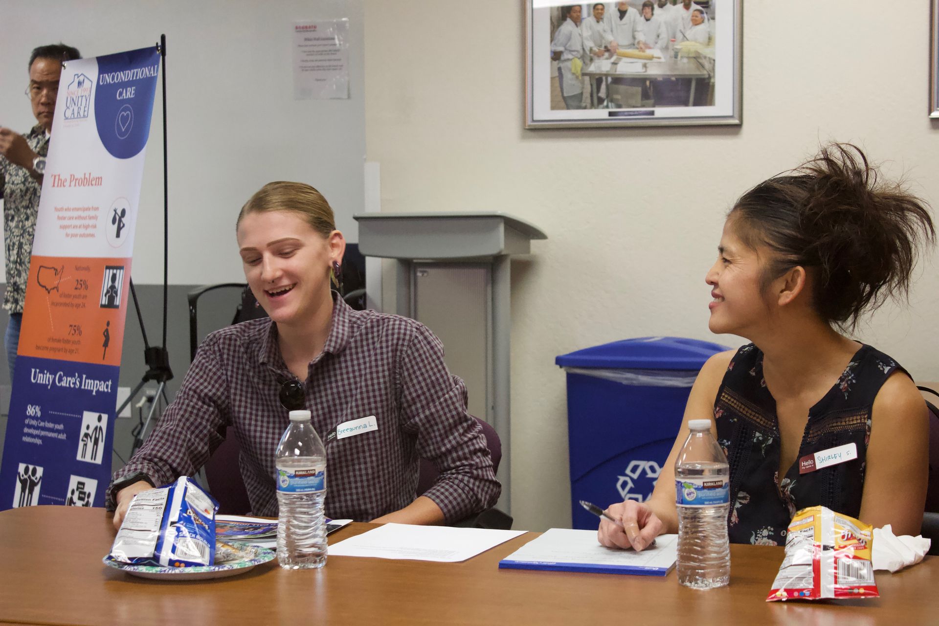 Two people seated at a table, smiling and talking during a community event