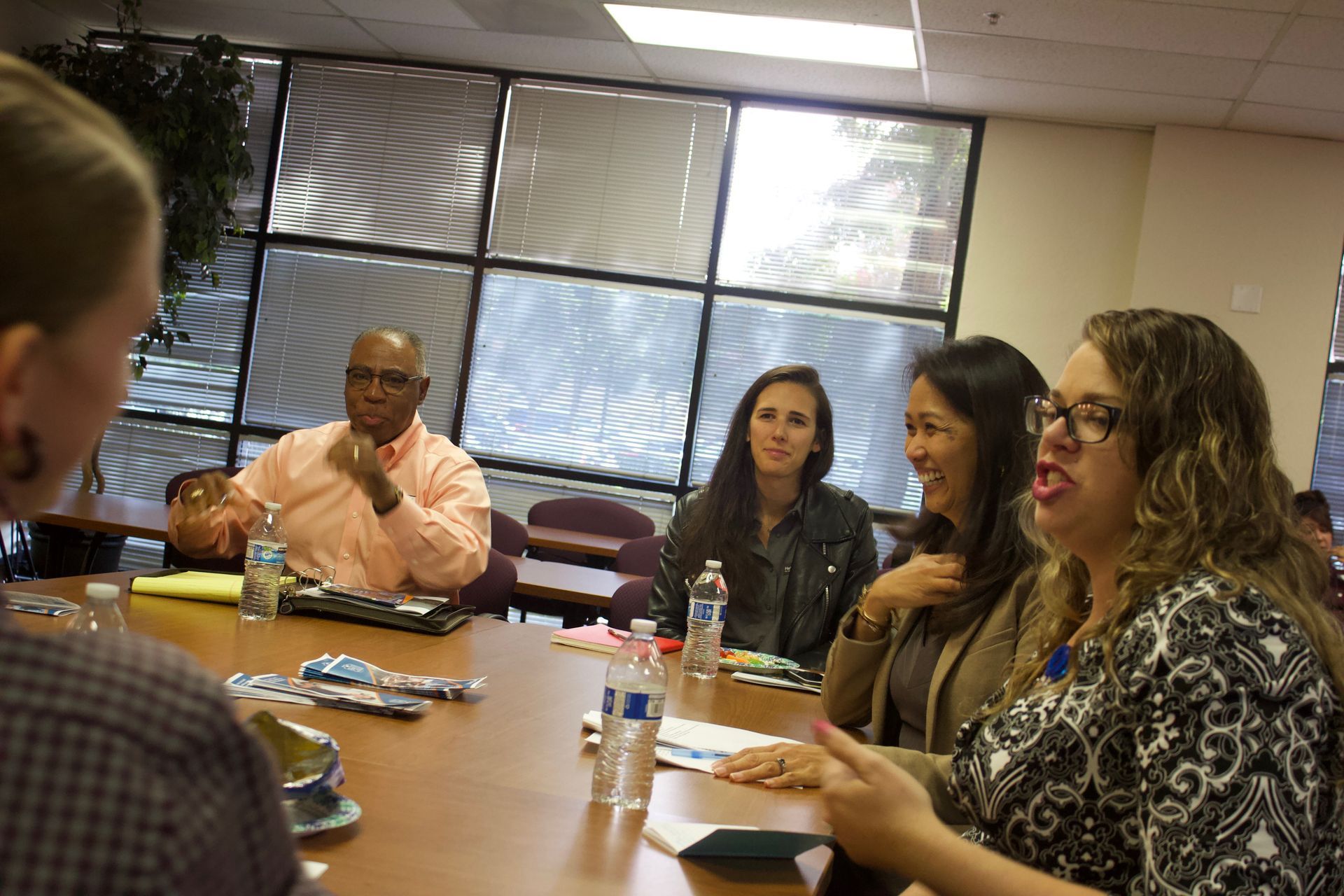 People seated around a conference table in a meeting room, talking and listening