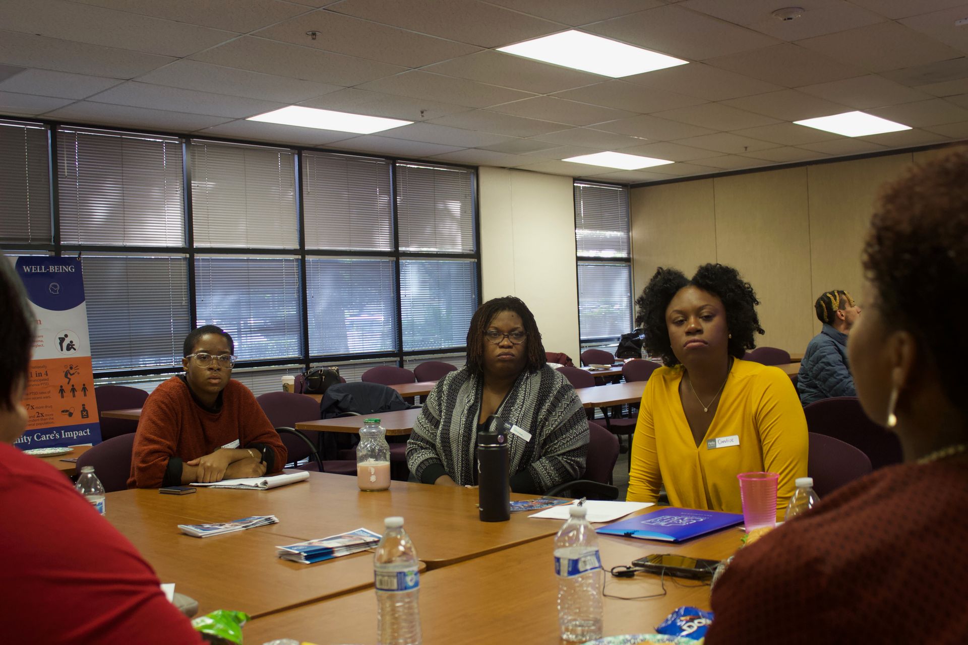 People seated around a conference table in a meeting room, talking with notebooks and drinks visible.