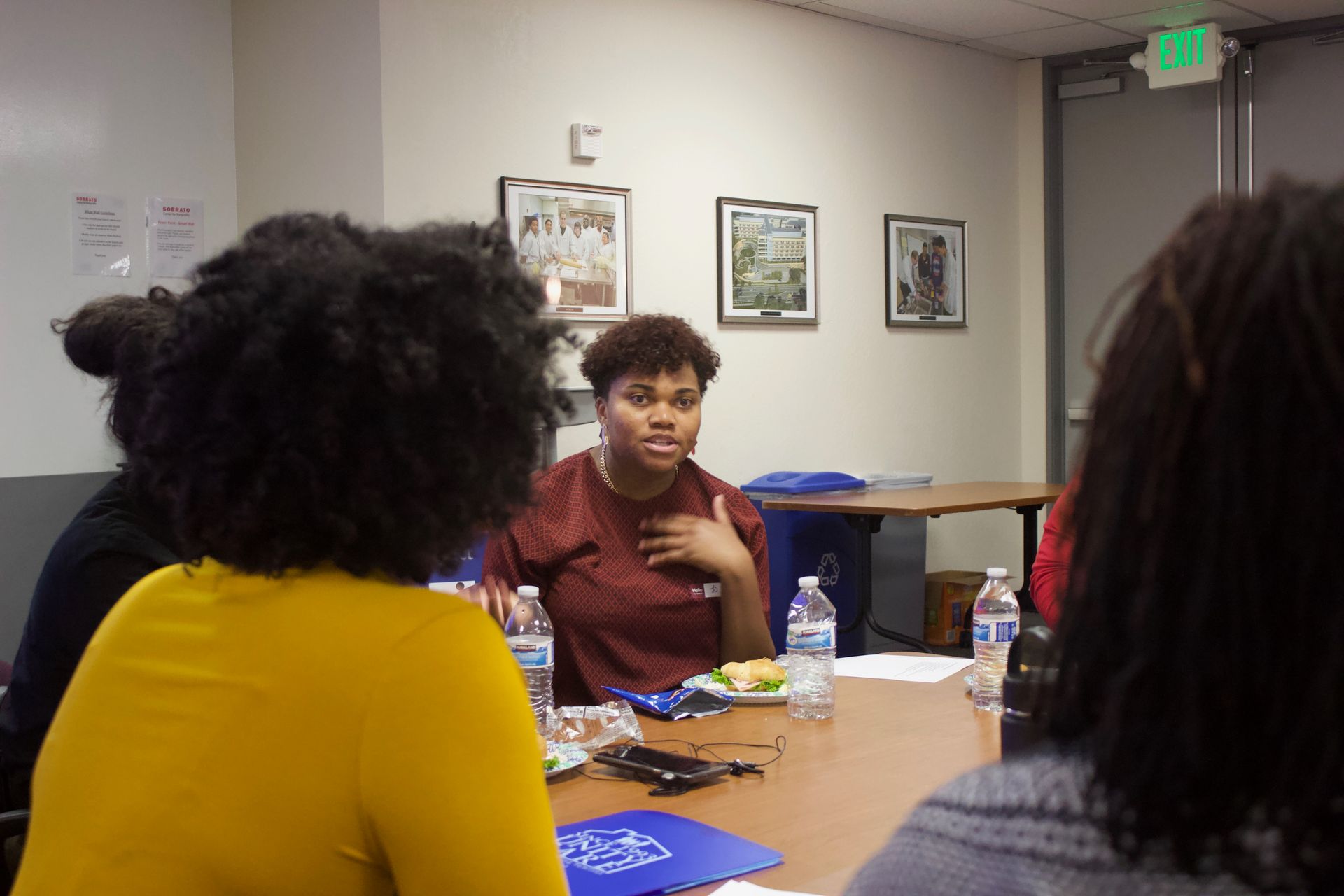 People seated around a table in a meeting room, with one person speaking and gesturing.
