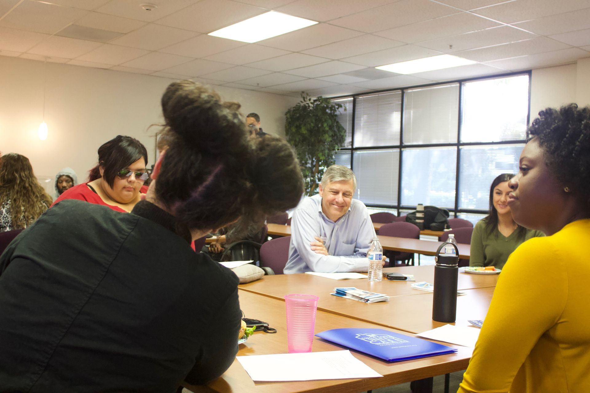 People seated around a conference table in a bright meeting room, discussing documents and a laptop.