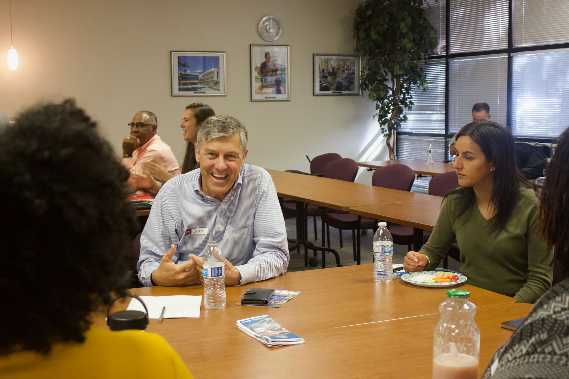 People seated around a conference table in a meeting room, discussing with papers and water bottles.