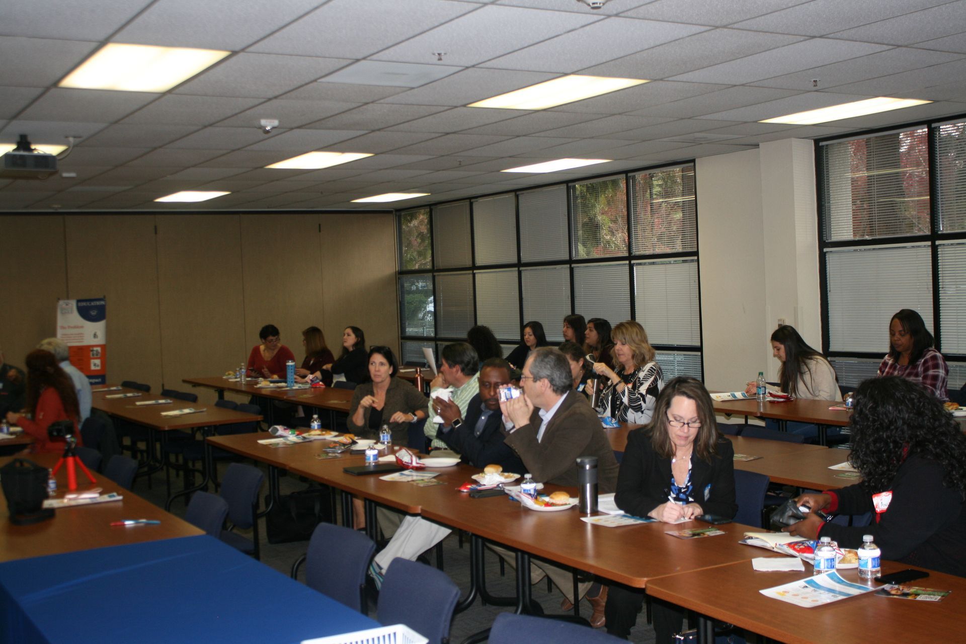 People seated at tables in a conference room during a meeting.