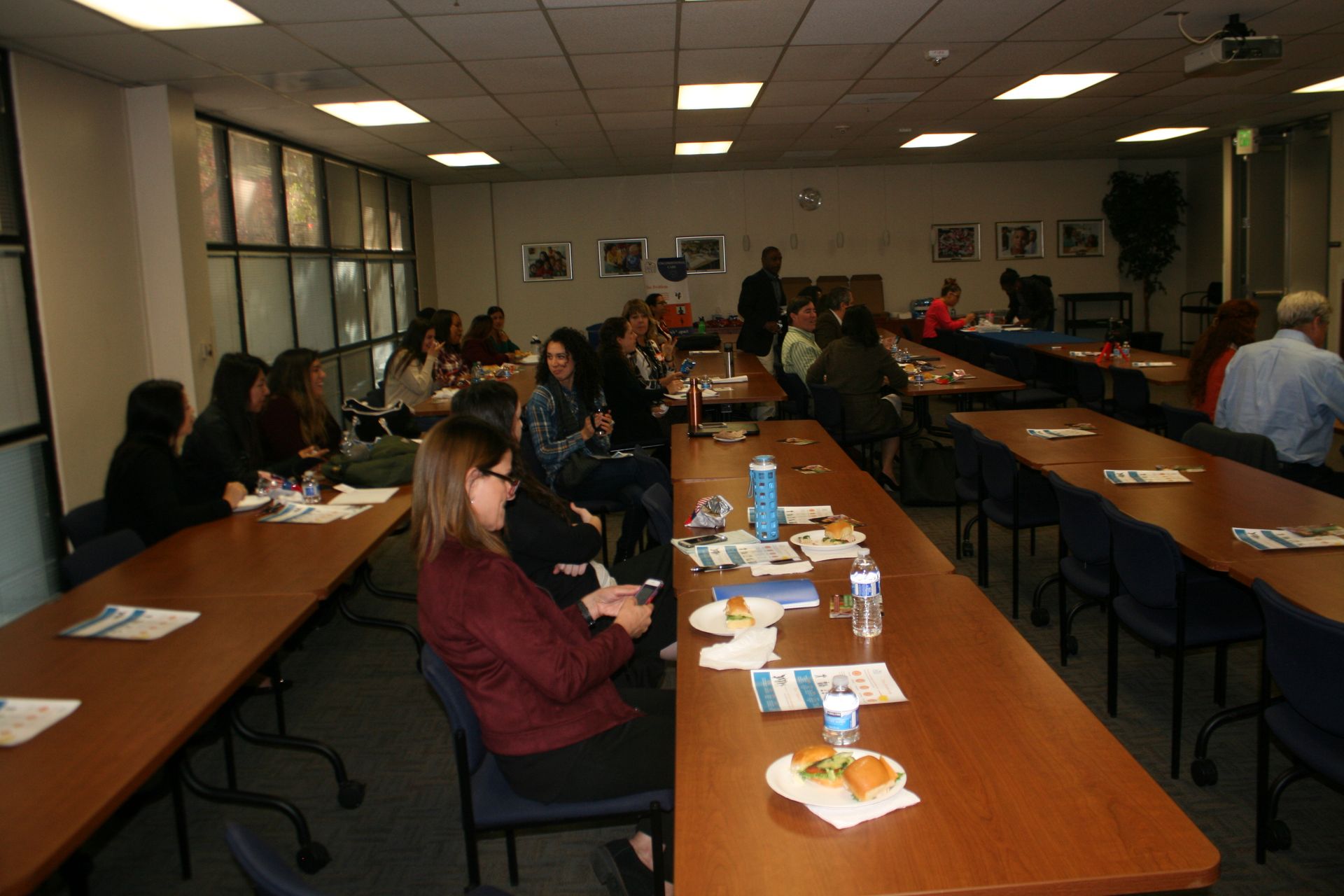 People seated around long tables in a conference room during a meeting or training session.