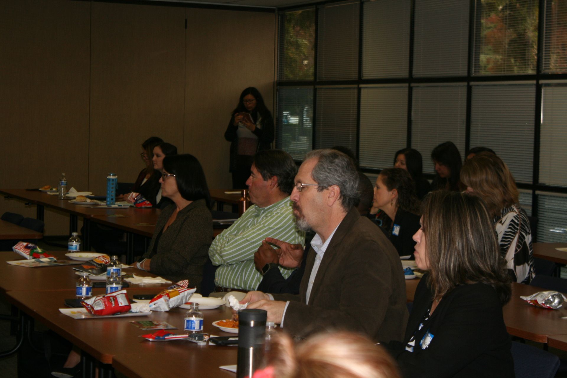 People seated at tables in a dimly lit restaurant or meeting room, talking and eating.