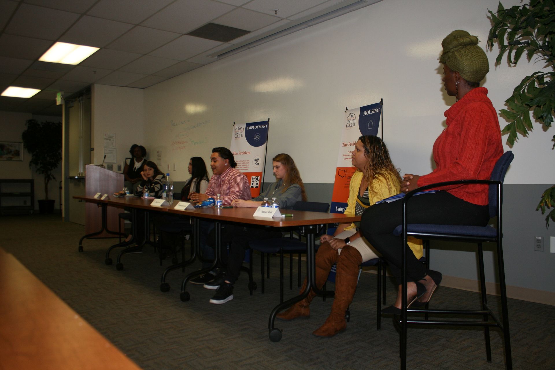 Panel discussion in a conference room with several speakers seated at a long table