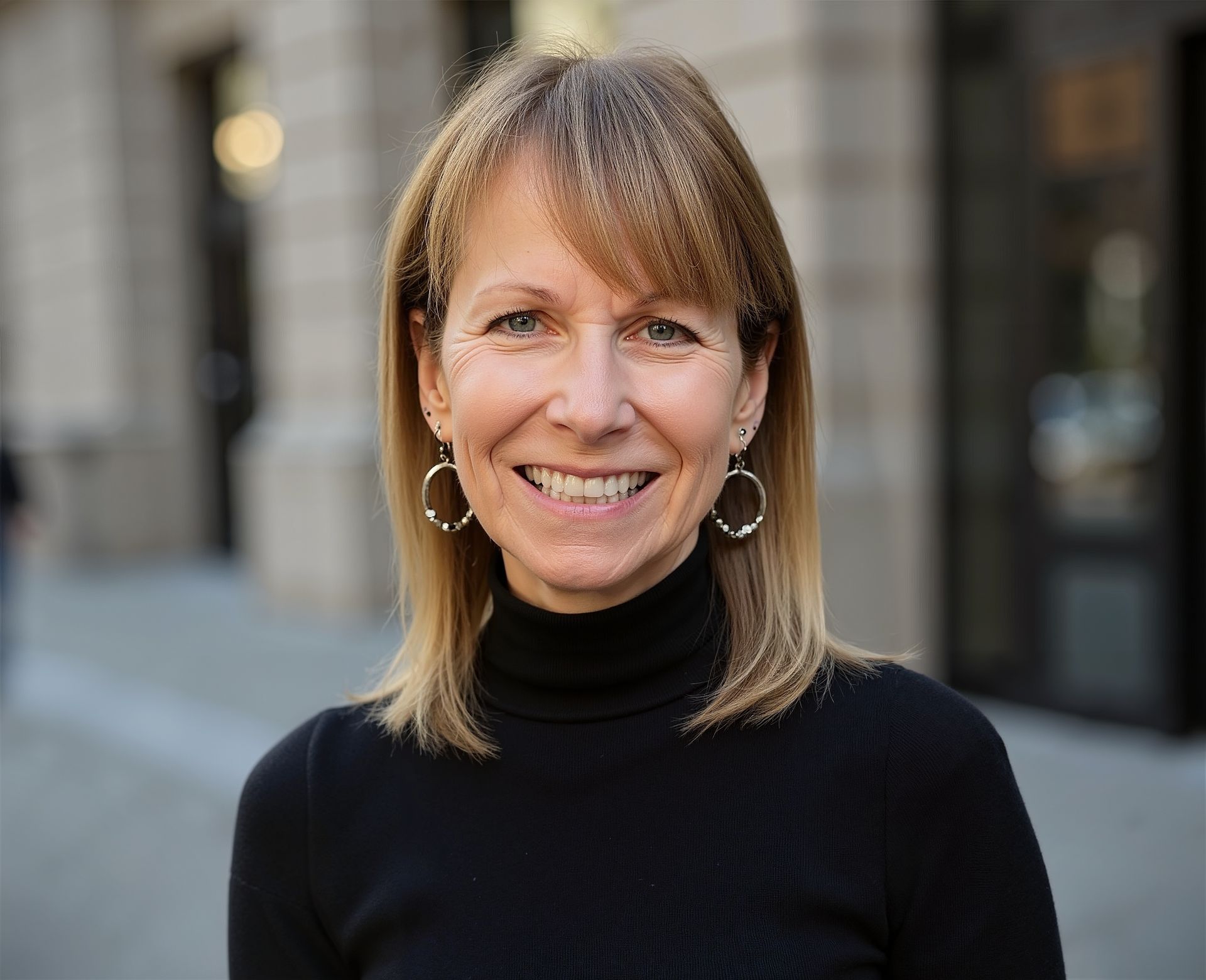 Smiling person in a black turtleneck standing outdoors on a city street