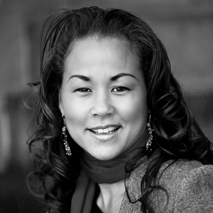 Black-and-white portrait of a smiling person with curly hair and dangling earrings
