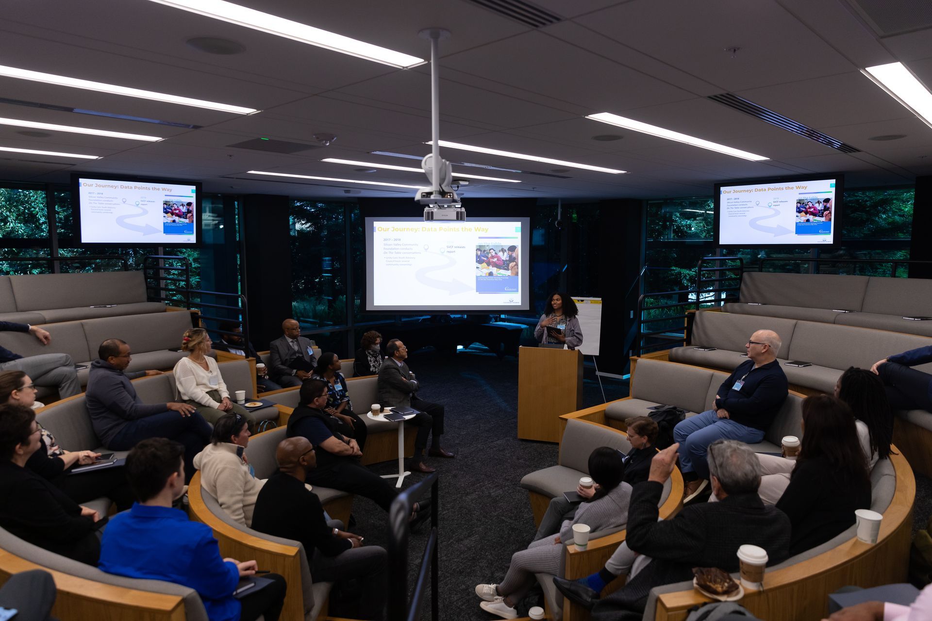 Conference room meeting with seated attendees watching a presentation on large screens