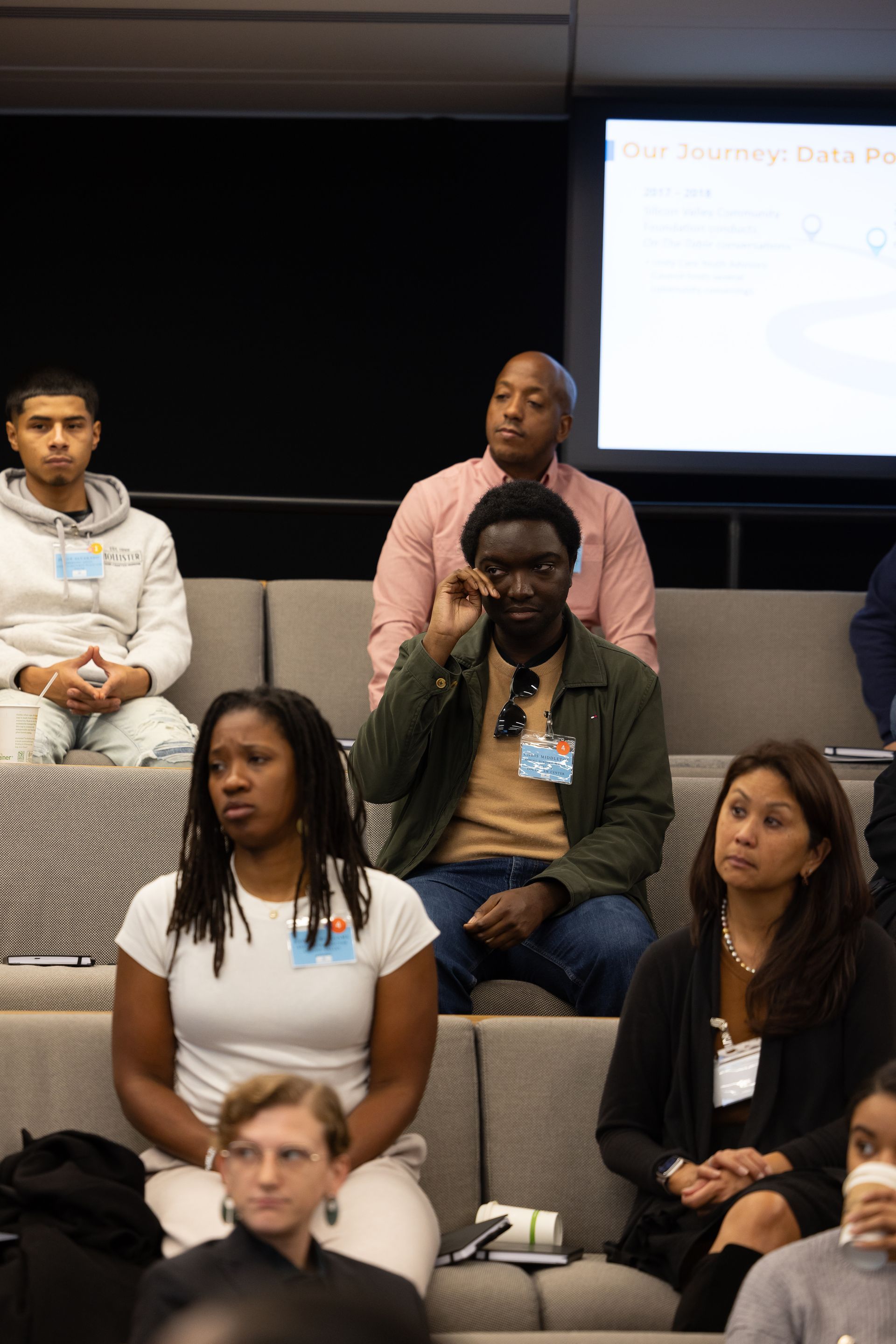 Audience seated in a lecture hall, listening attentively.