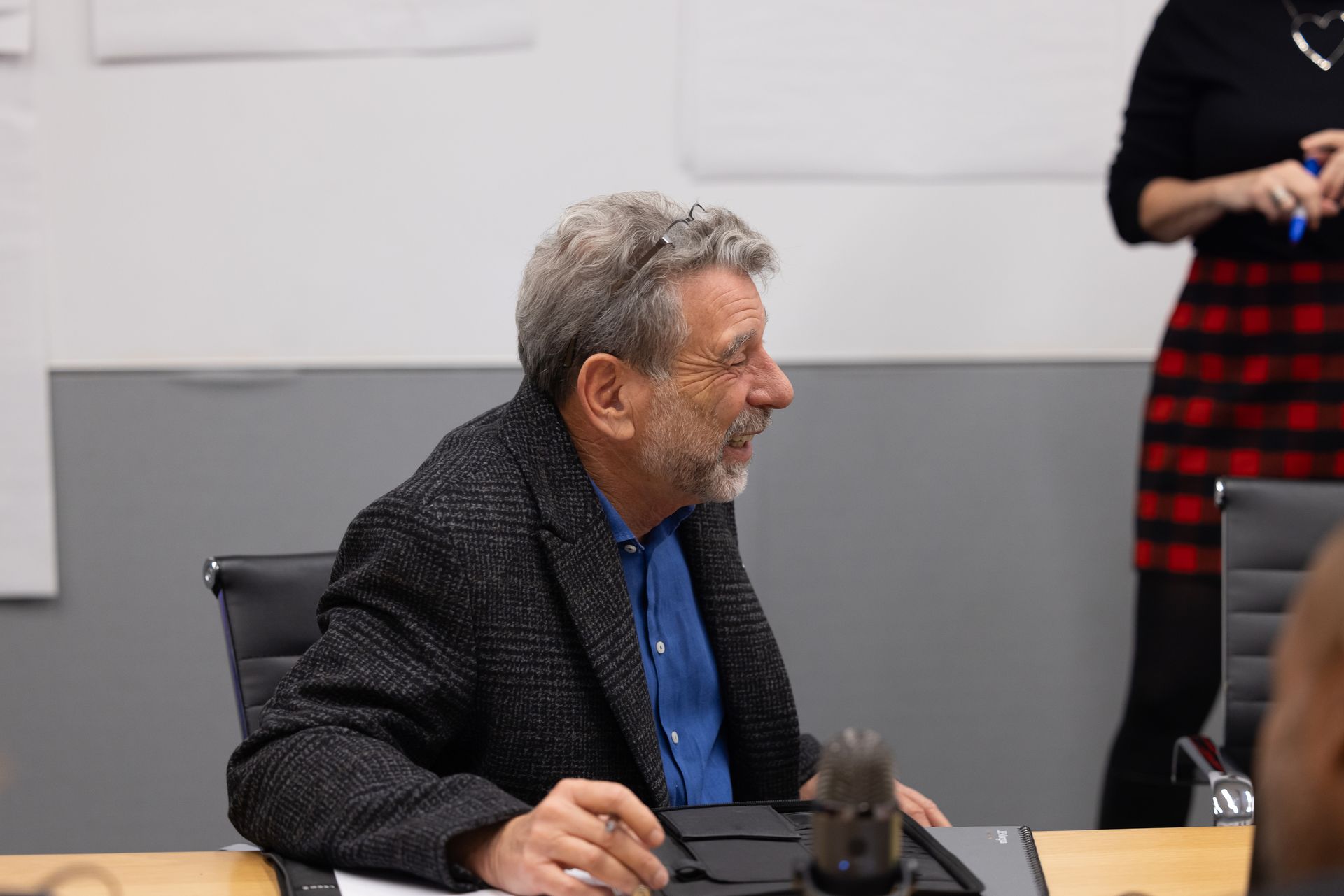 Man seated at a conference table, smiling in a gray-walled meeting room