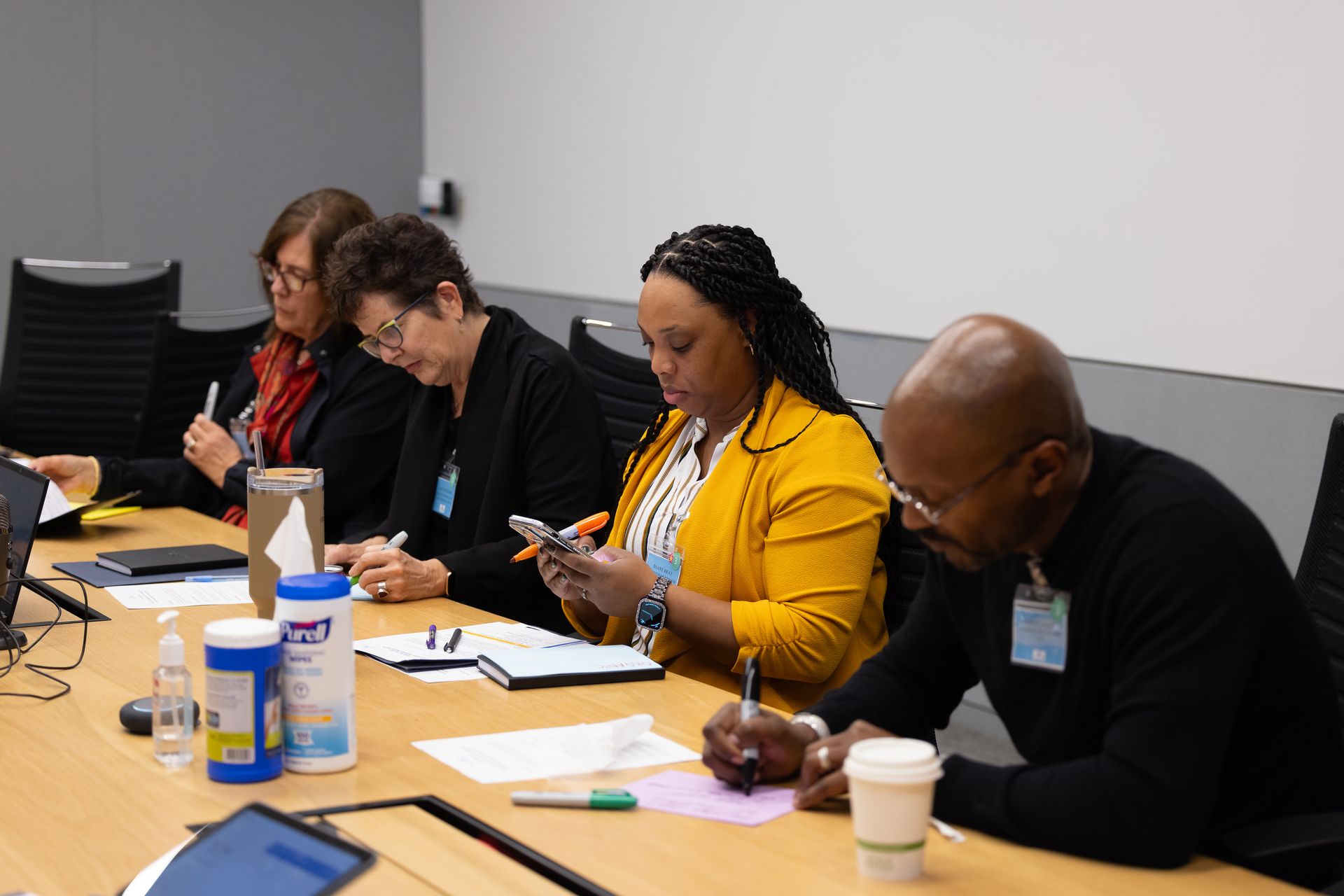 People seated at a conference table taking notes during a meeting.
