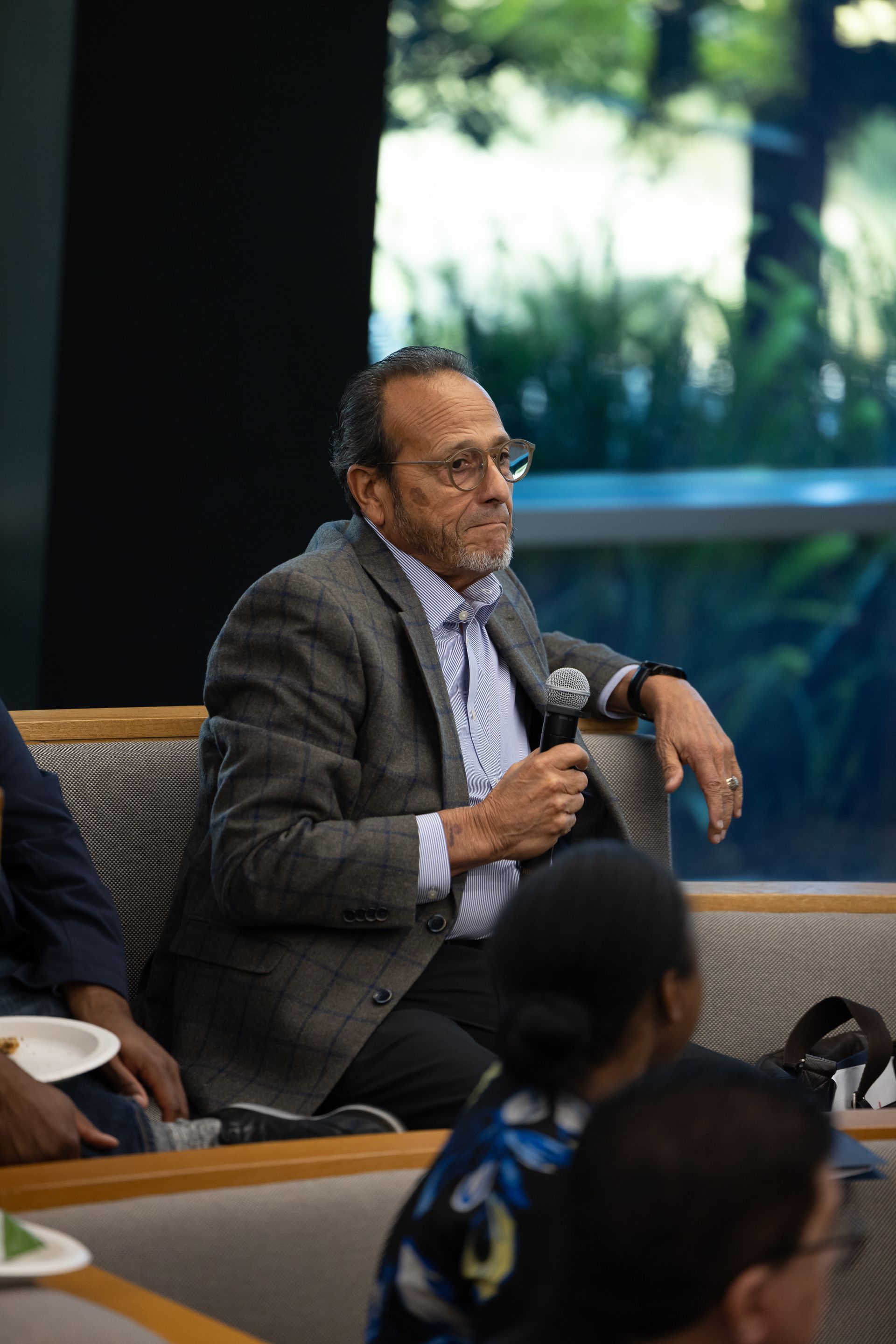 Man speaking into a microphone while seated in a modern conference room