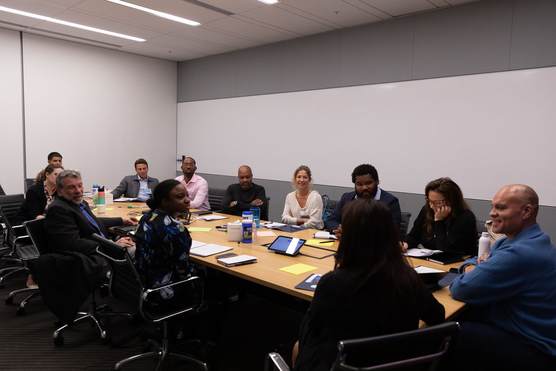 People seated around a conference table in a meeting room, discussing with laptops and papers.