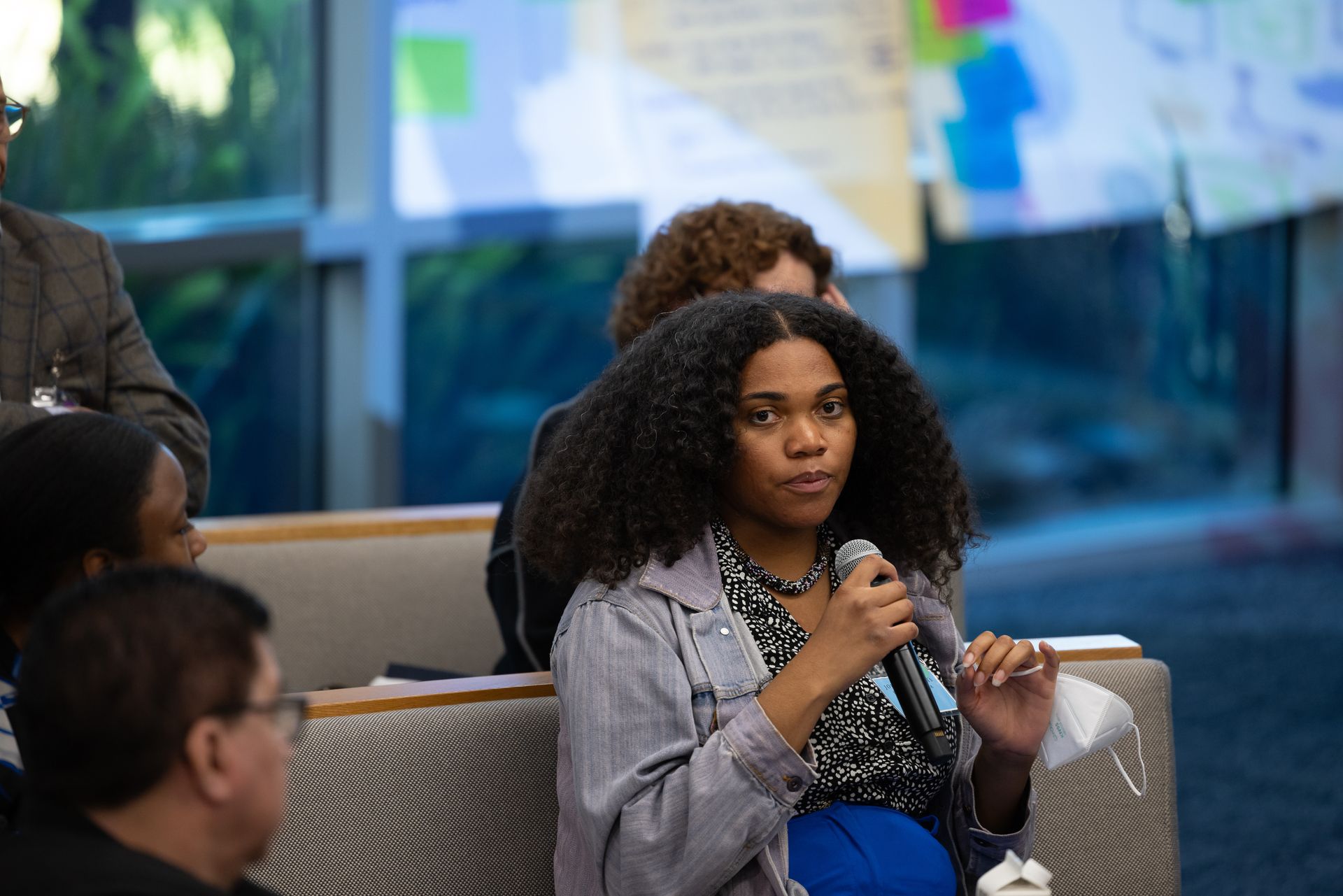 Woman speaking into a microphone during a discussion in a modern indoor setting