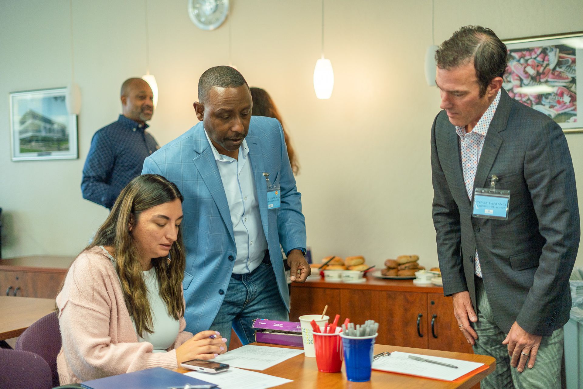 People reviewing documents at a table in a meeting room, with pens, papers, and coffee cups nearby.