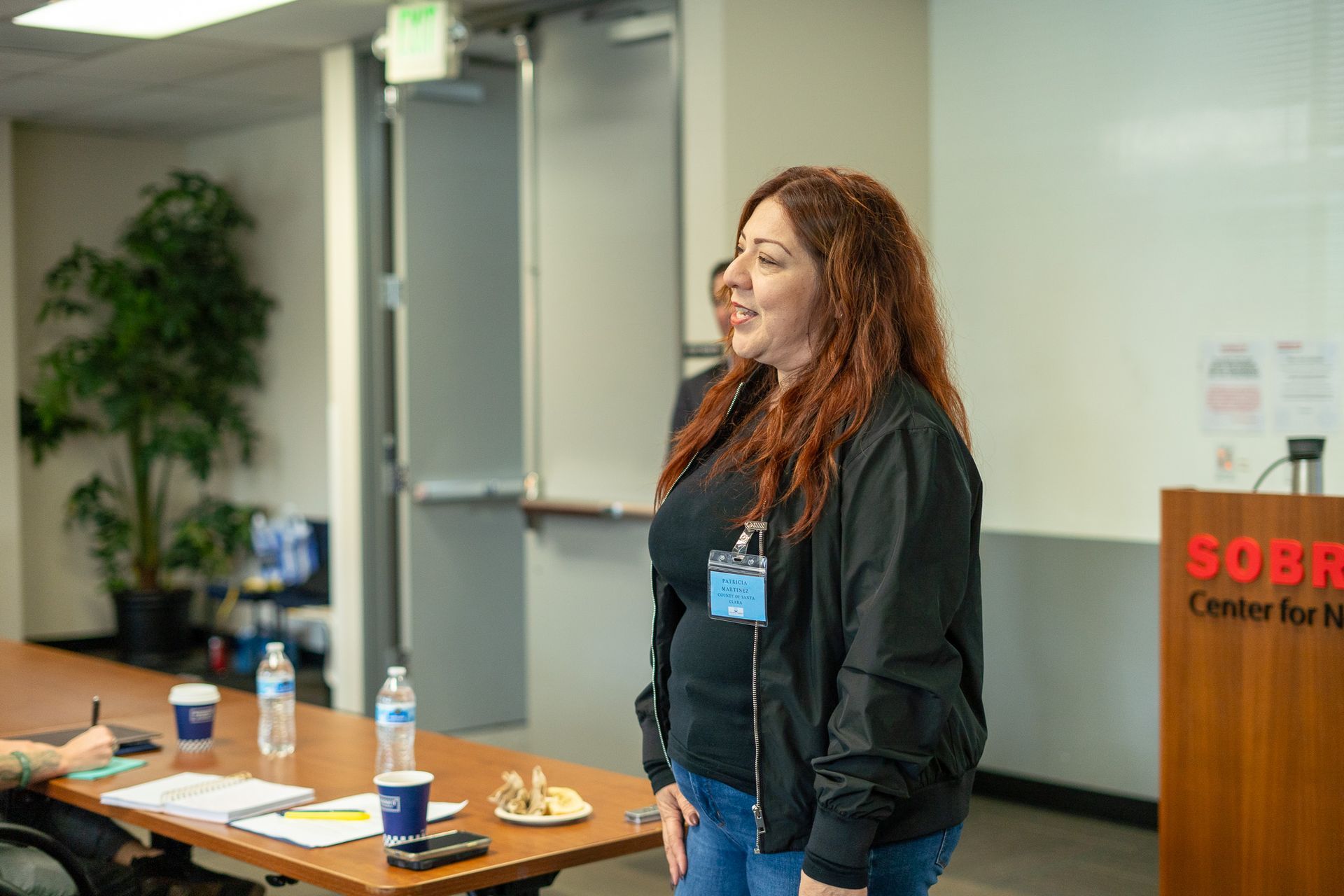 Woman speaking beside a table with drinks in a conference room