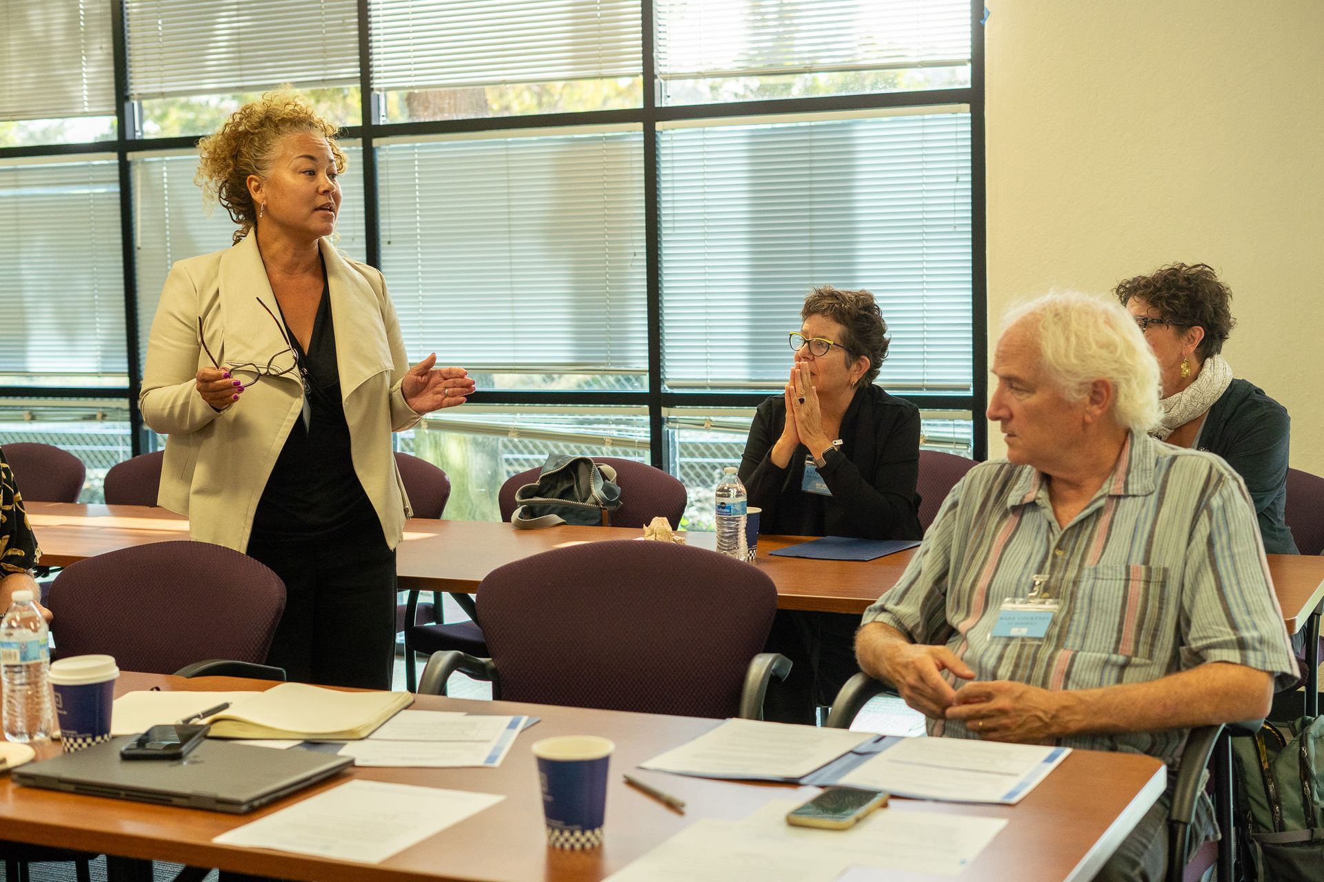 Woman speaking at a conference table while others listen in a meeting room