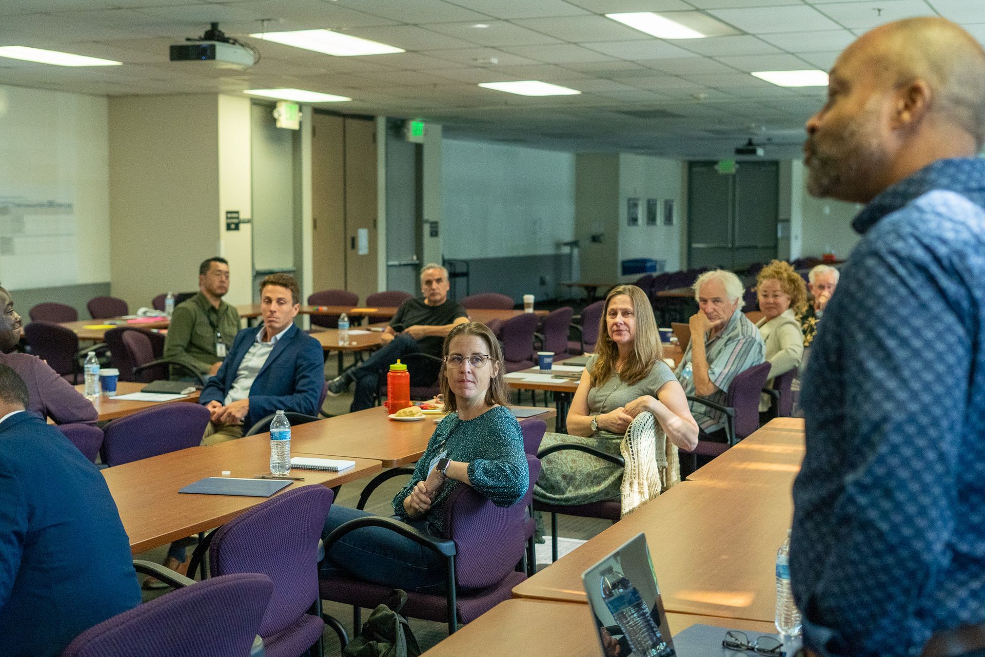People seated in a classroom listening to a speaker at the front of the room