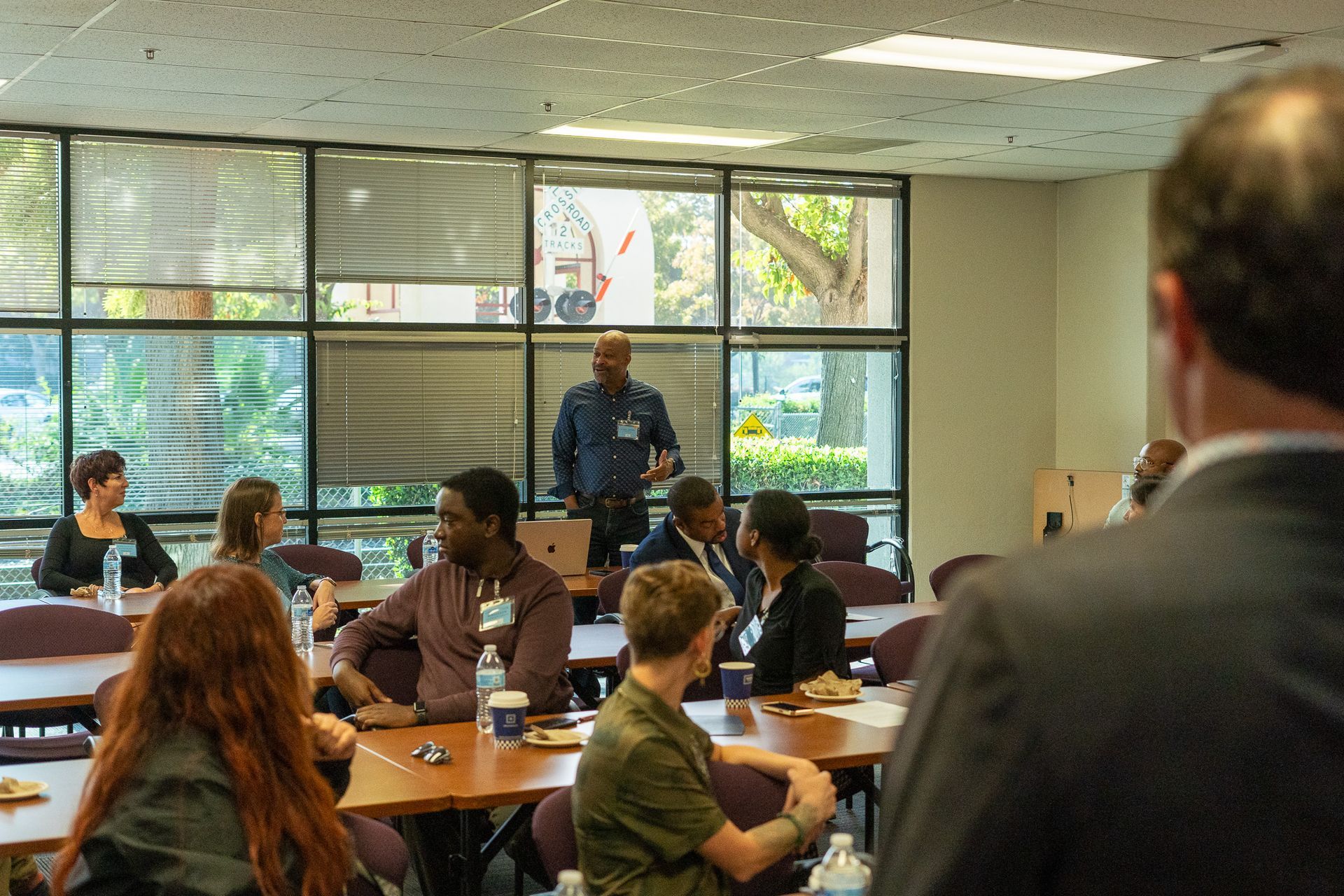Classroom presentation with speaker at front and audience seated at desks in a bright room