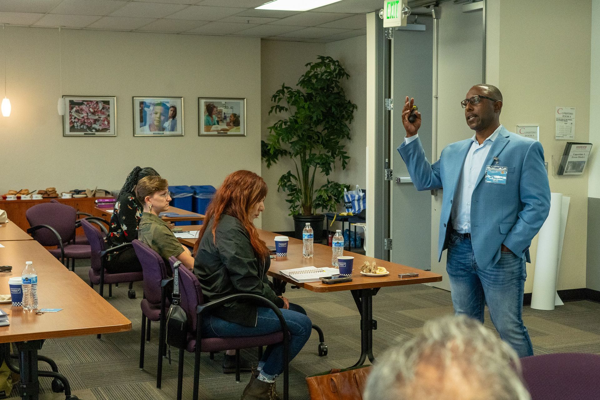 Man in blue suit speaking to seated audience in a meeting room