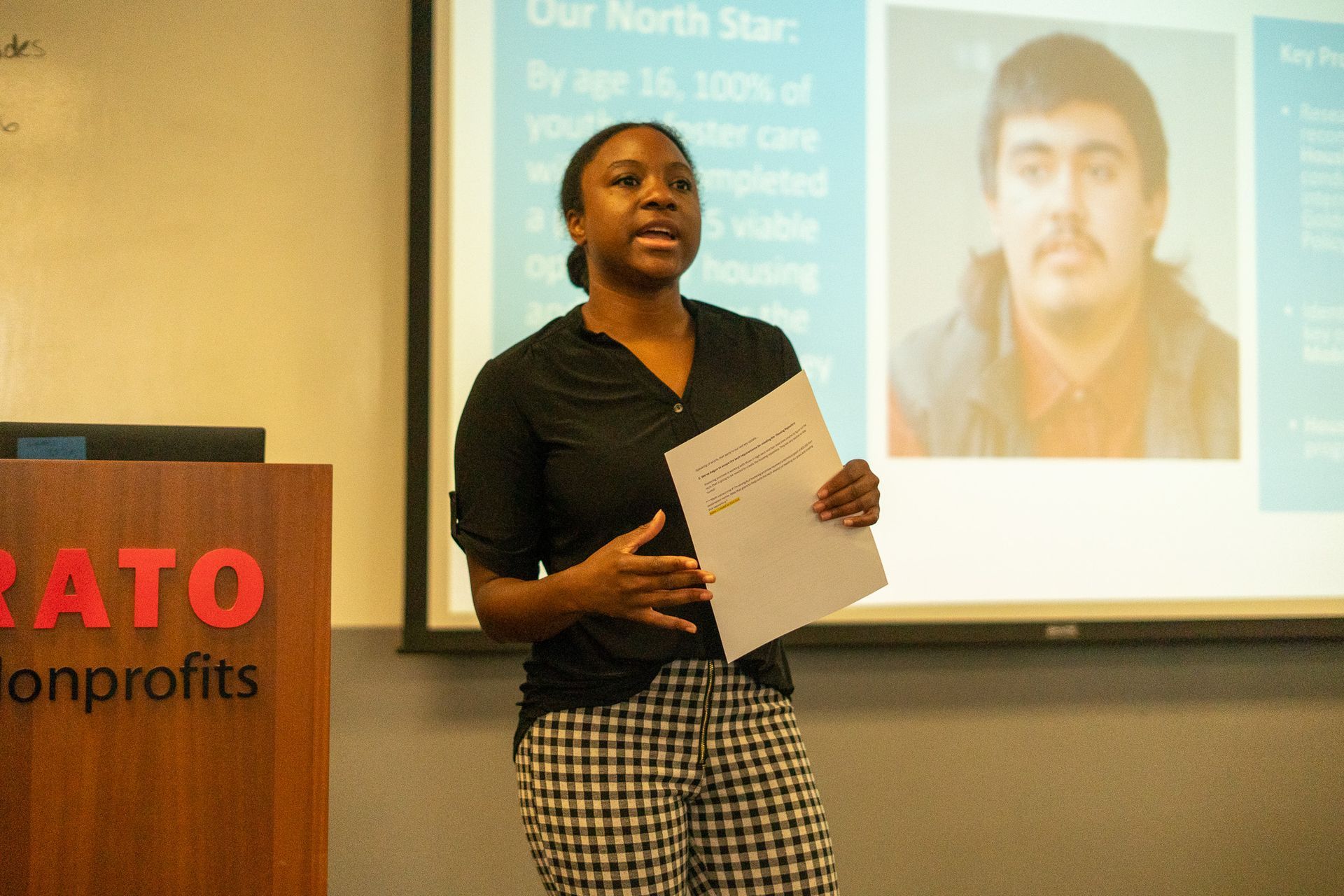 Speaker presenting beside projected photo at a nonprofit event
