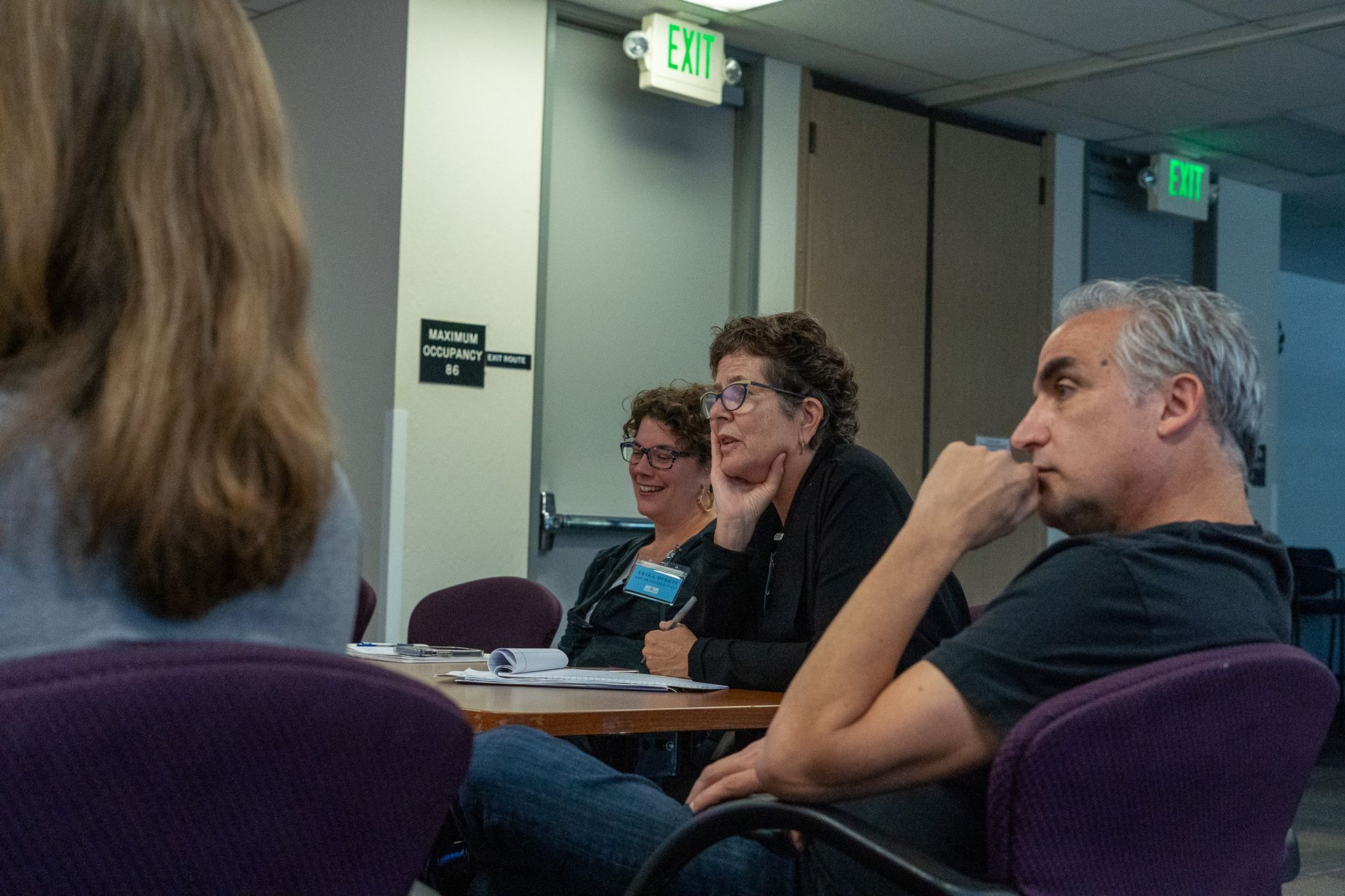 People seated in a conference room, listening during a meeting.