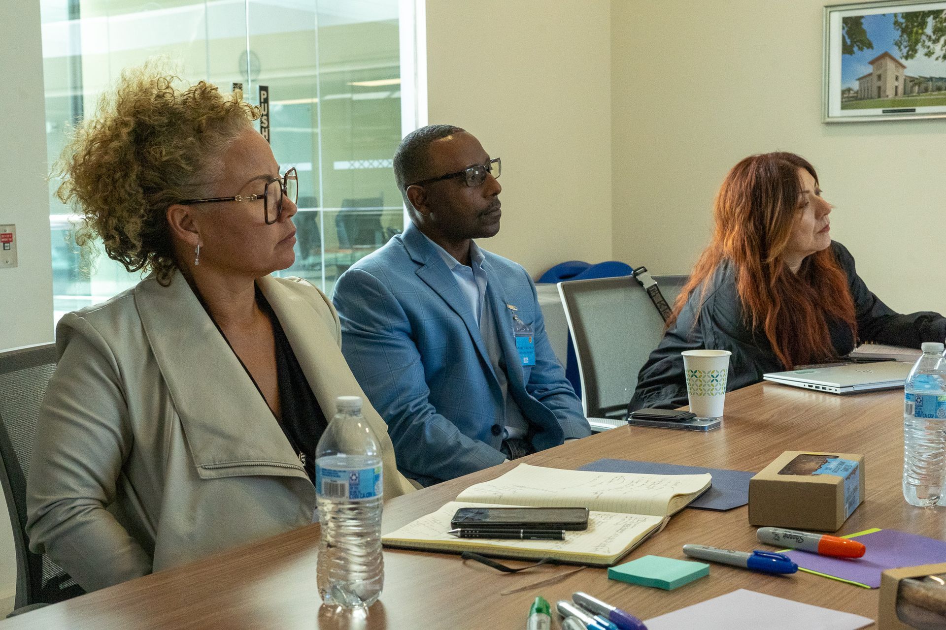 People seated at a conference table in a meeting room, listening attentively.