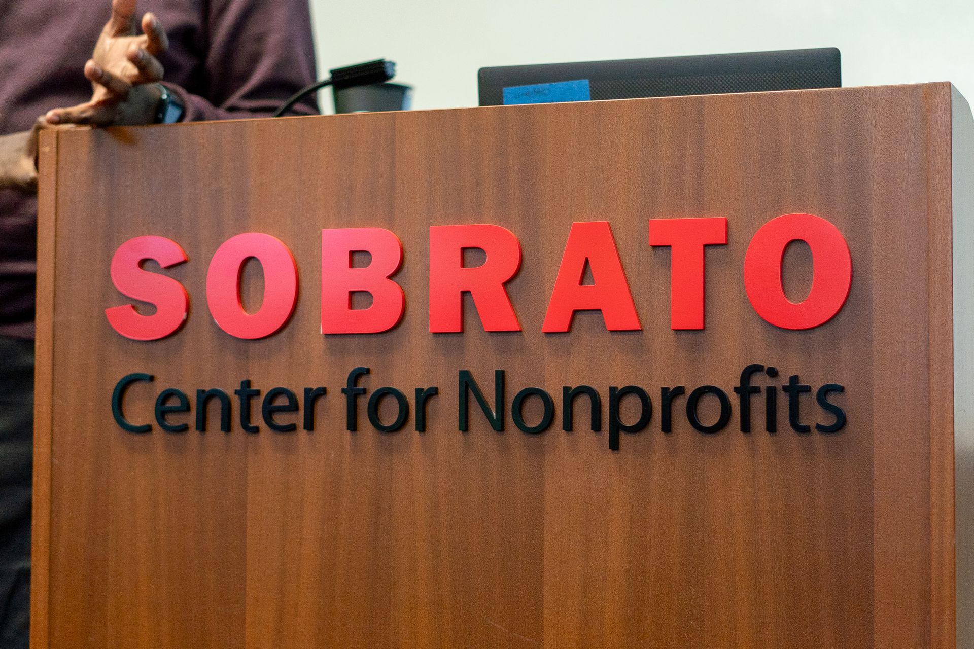 Sobrato Center for Nonprofits sign on a wood-paneled wall, with red letters and black subtitle text.