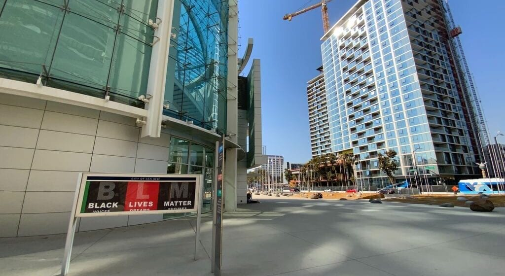 Street view of modern buildings and a construction site under a clear blue sky