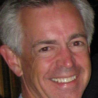 Smiling gray-haired man in a close-up portrait against a dark background
