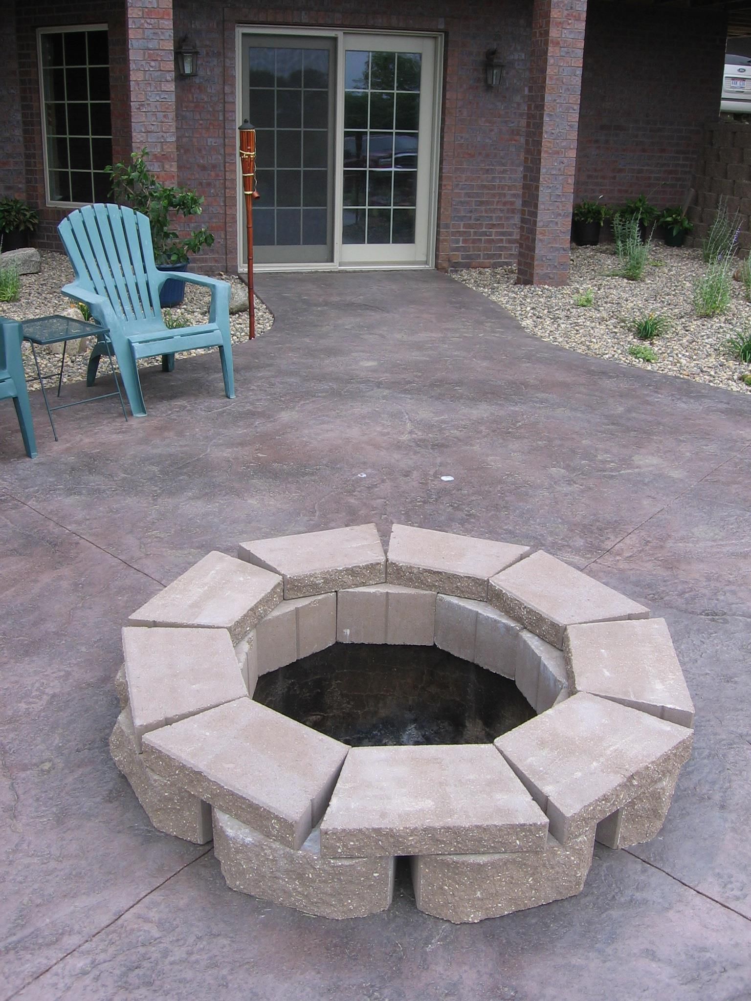 A fire pit on a patio in front of a brick house