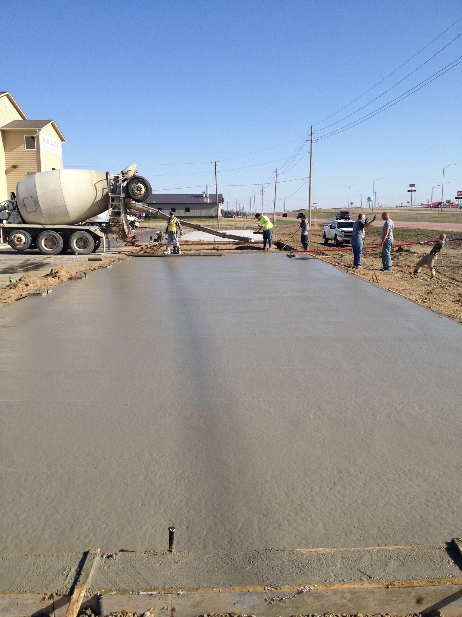 A concrete truck is pouring concrete on a road