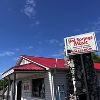 A white house with a red roof and a sign for hot springs music.