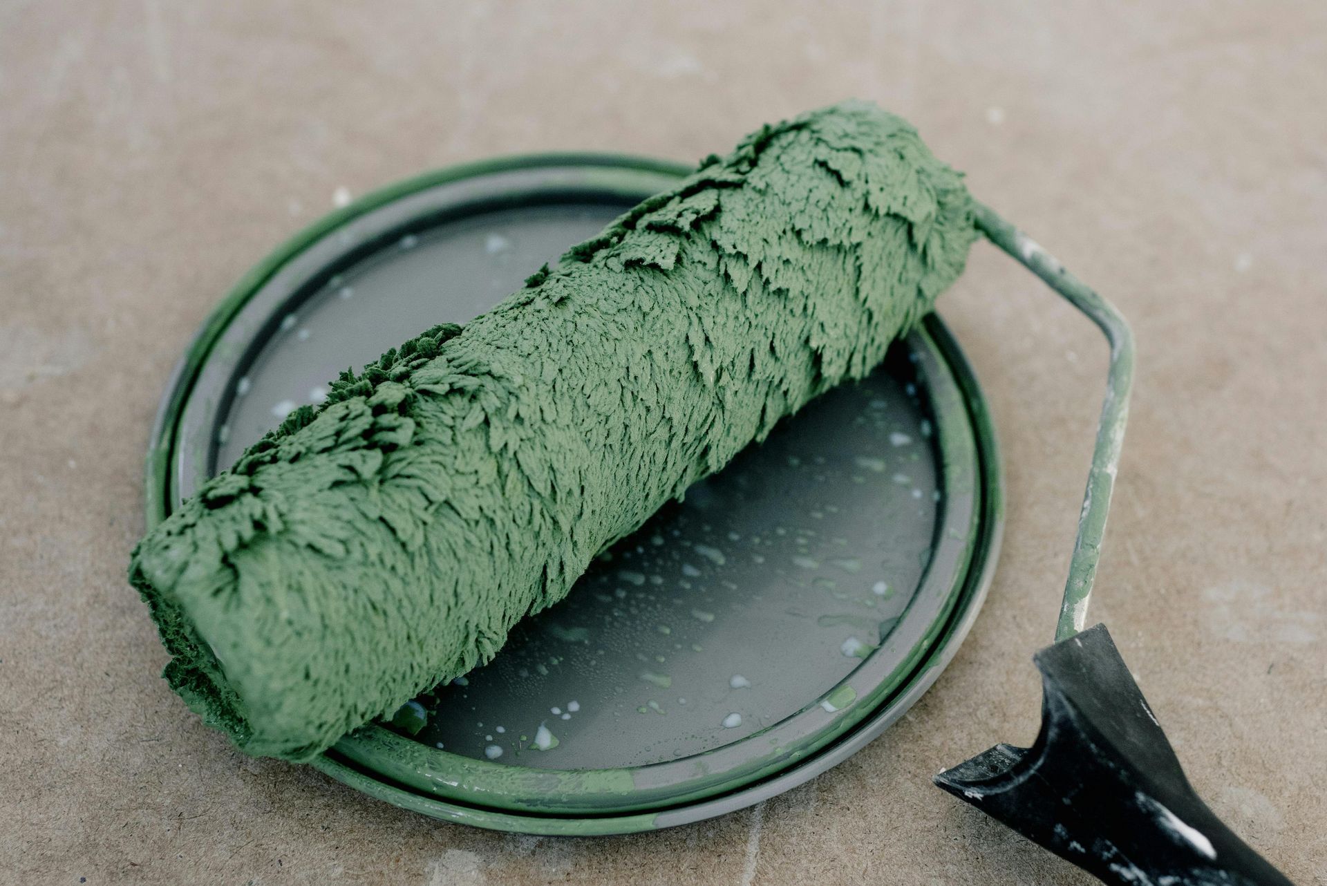 A green paint roller is sitting on top of a black plate.
