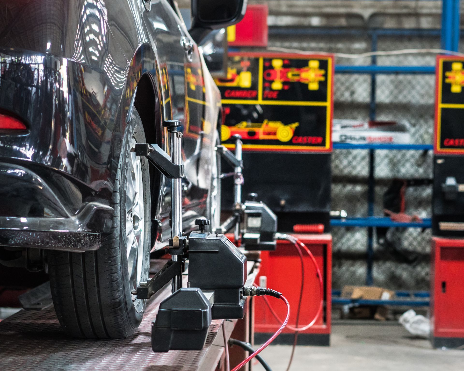 Car undergoing wheel alignment in a garage, with alignment equipment attached to the wheels.