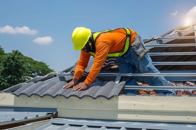 A construction worker is working on the roof of a building.