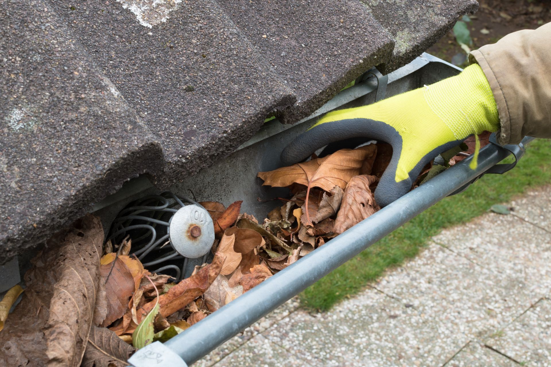 A person is cleaning a gutter with a leaf blower.