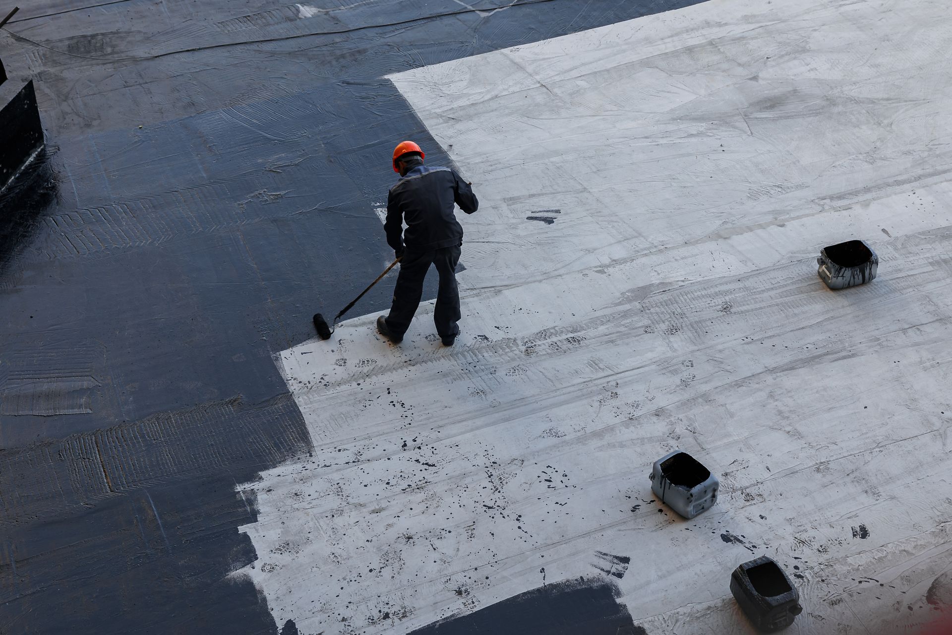 A man is painting a roof with a roller.