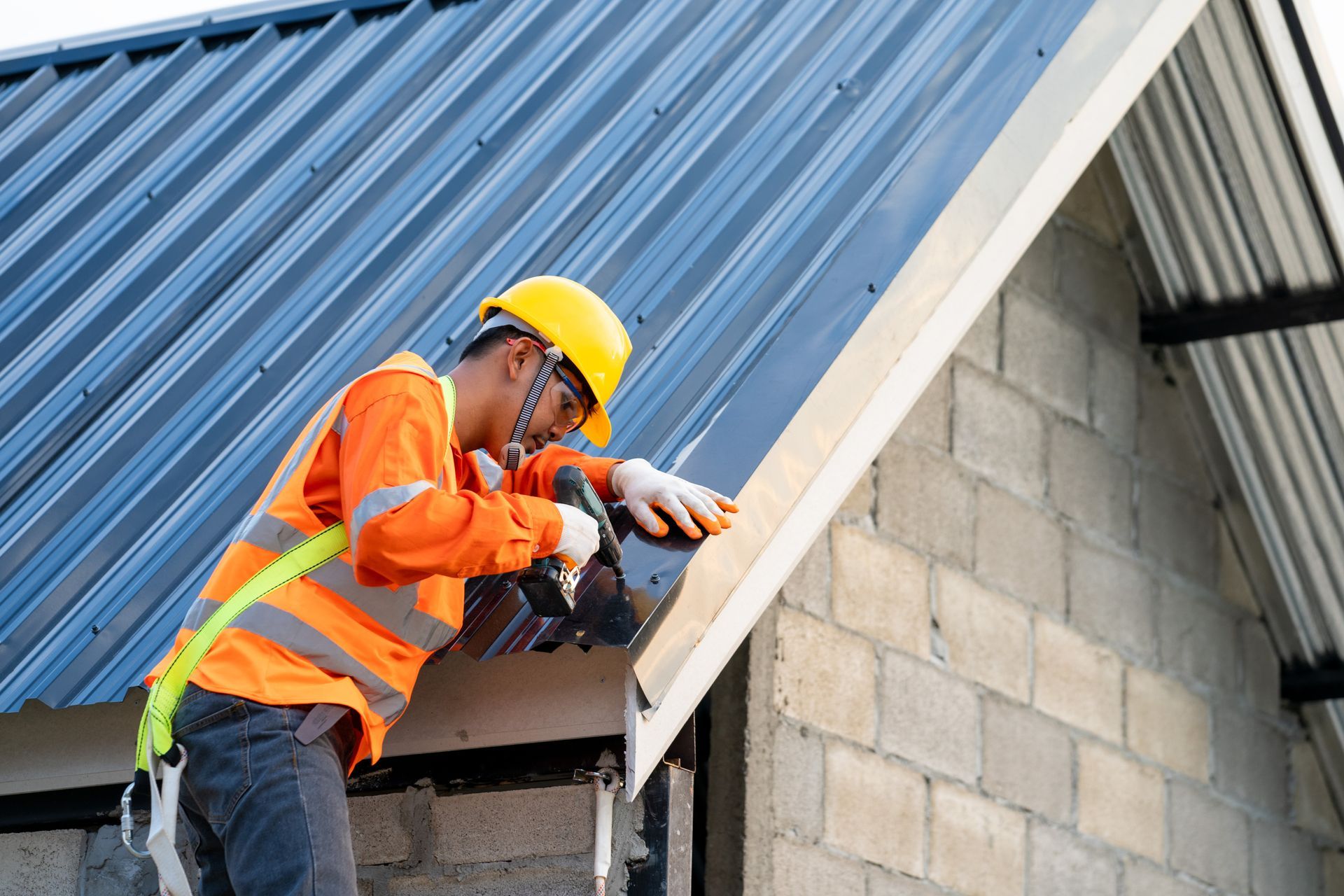 A construction worker is installing a metal roof on a house.