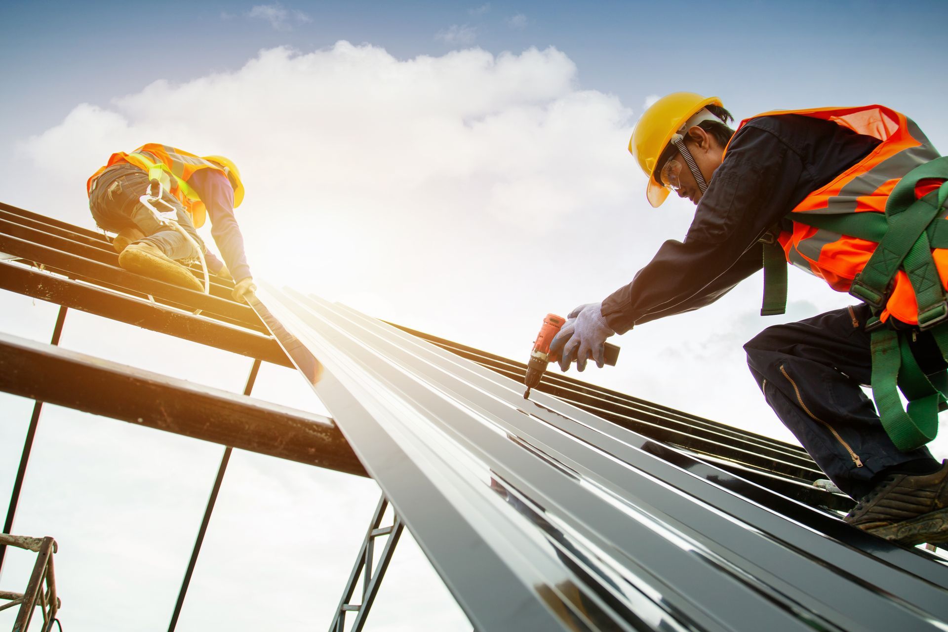 Two construction workers are working on the roof of a building.