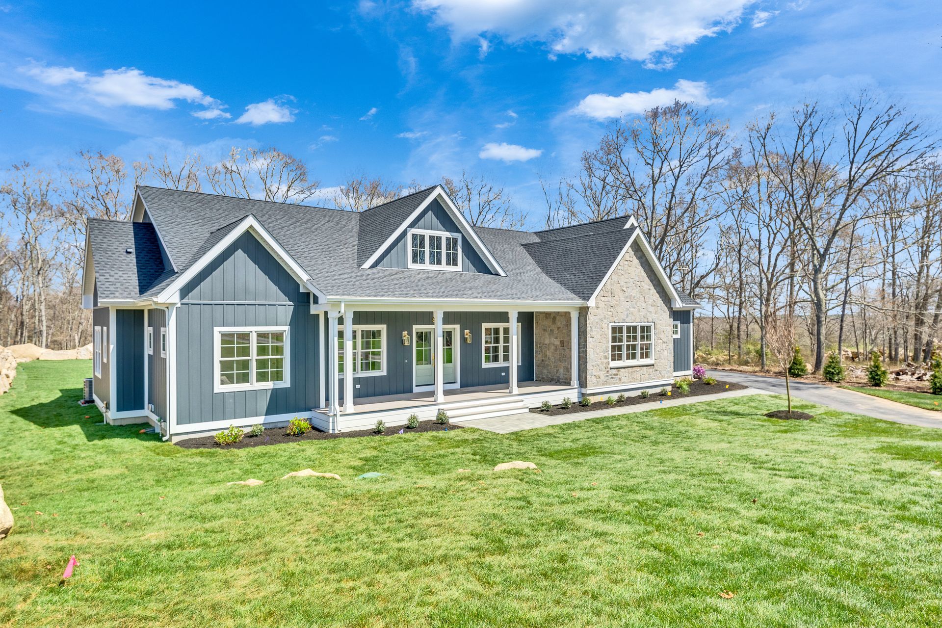 Gray house with white trim and a large green lawn under a clear blue sky