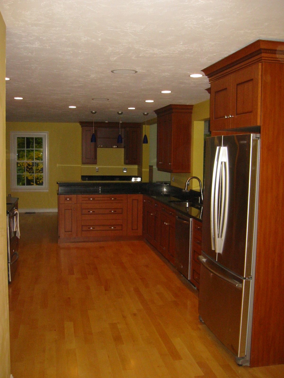 Kitchen with wood cabinets, stainless steel appliances, and yellow walls.