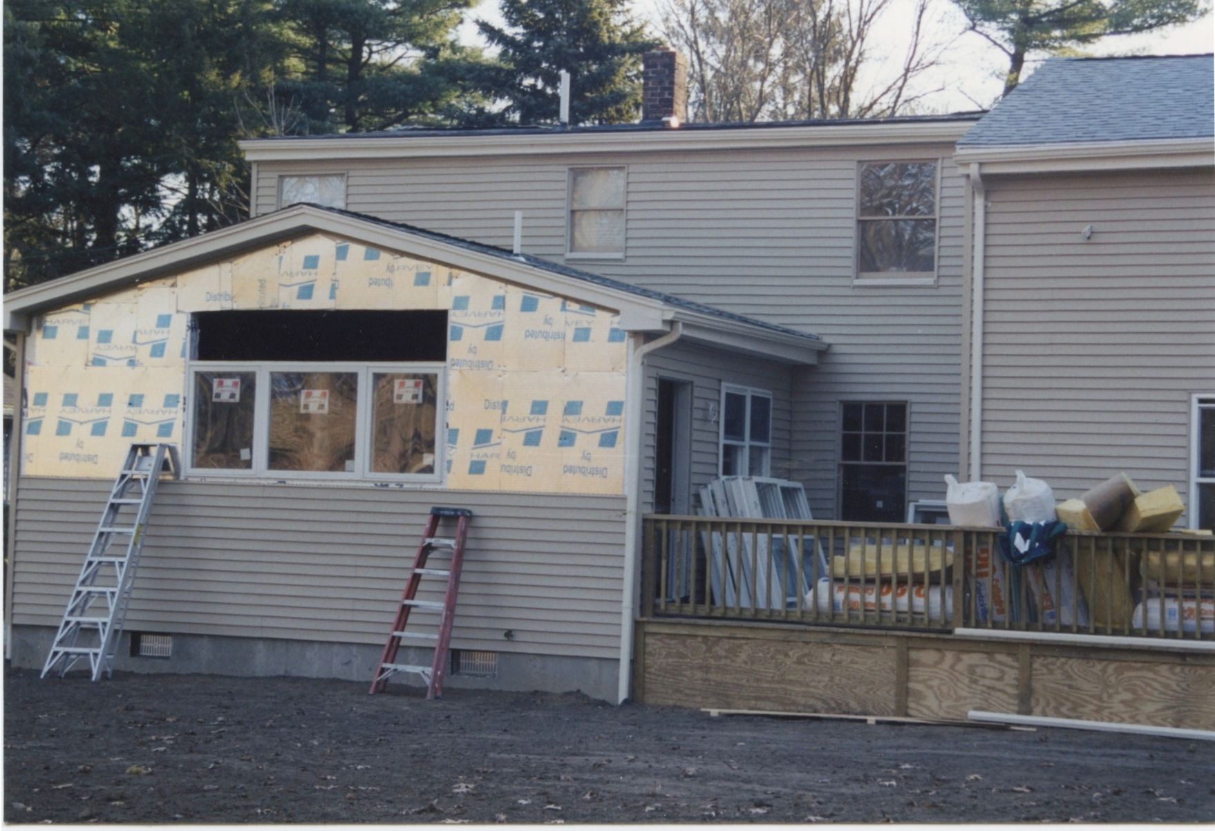House under construction, with siding and insulation visible, ladders present.