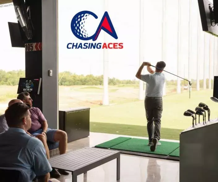 A man is swinging a golf club in a room that says chasing aces