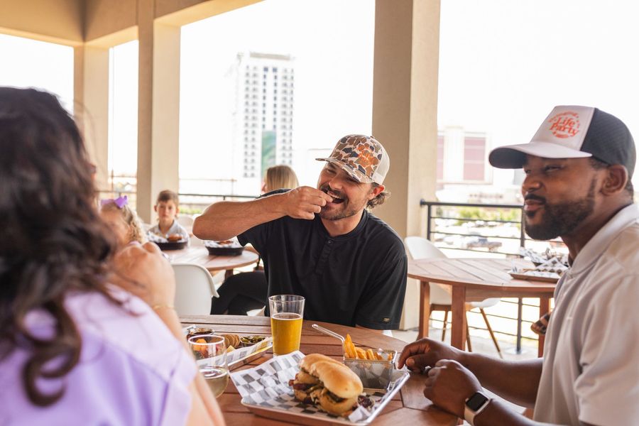 A group of people are sitting at a table eating food and drinking beer.