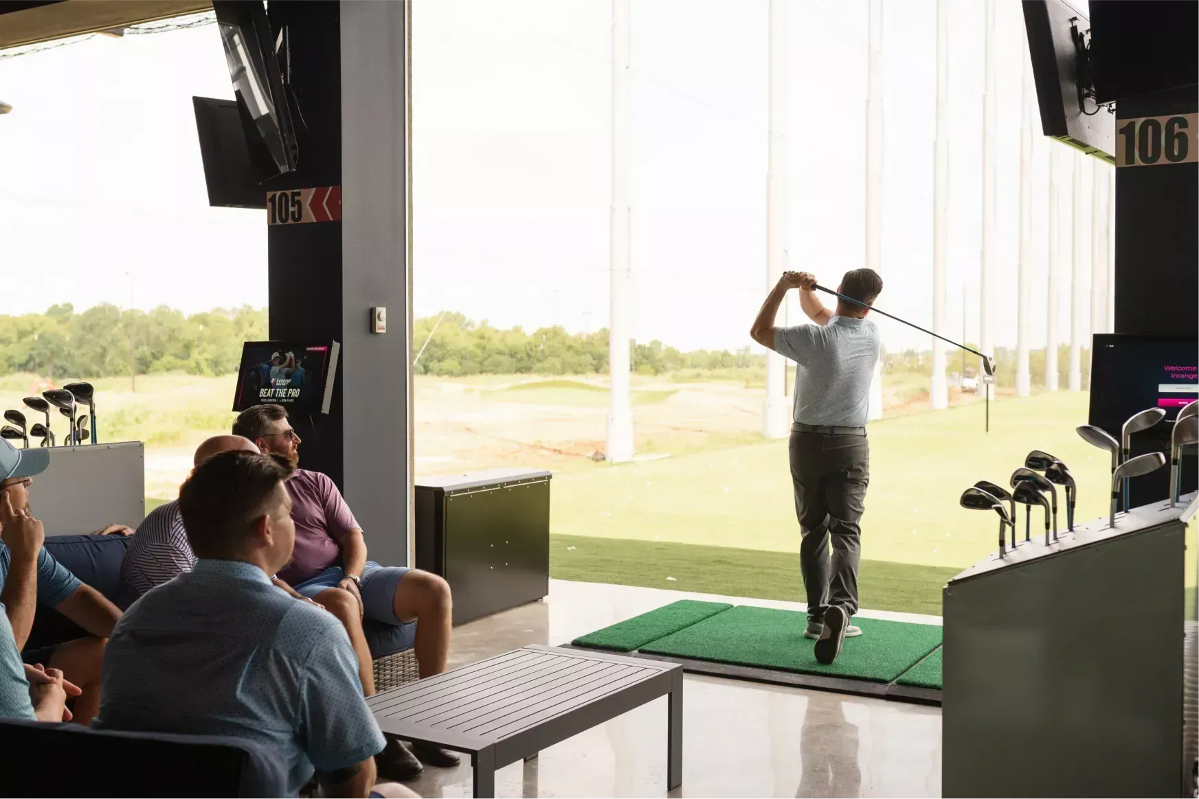 A man is swinging a golf club at a golf course while a group of people watch.